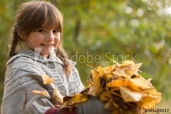 Portrait cute girl holding autumn leaves in park