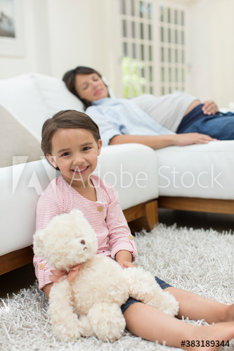 Portrait cute girl with teddy bear by sleeping pregnant mother