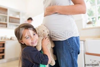 Portrait cute girl with teddy bear listening to stomach of pregnant mother