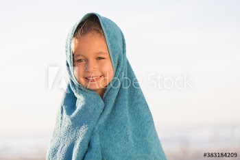 Portrait cute girl wrapped in towel on sunny beach