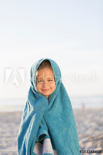 Portrait cute girl wrapped in towel on sunny beach