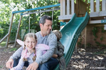 Portrait father and kids on slide in backyard