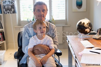 Portrait father holding son on lap in home office