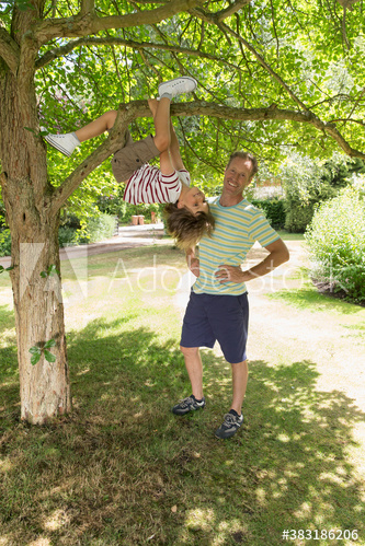 Portrait father watching son climbing tree in park