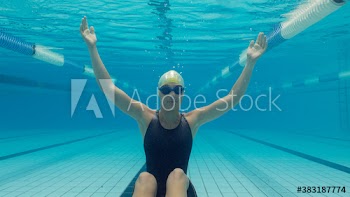 Portrait female swimmer sitting underwater in swimming pool