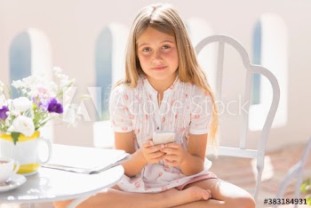 Portrait girl using smart phone on sunny balcony