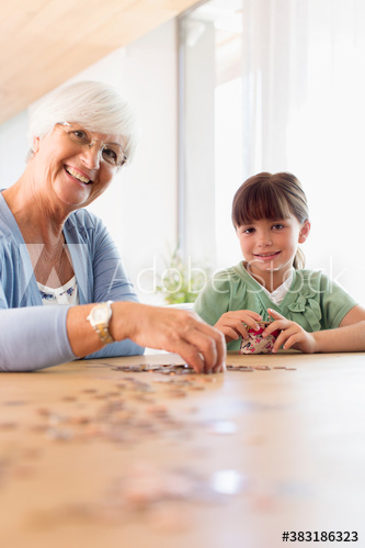 Portrait grandmother and granddaughter counting coins at table