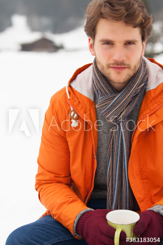 Portrait handsome young man drinking coffee in snow