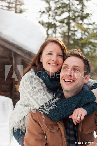 Portrait happy affectionate couple hugging outside snowy cabin
