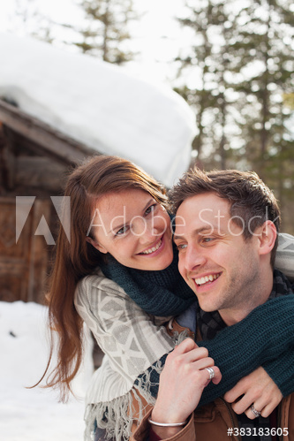 Portrait happy affectionate couple hugging outside snowy cabin