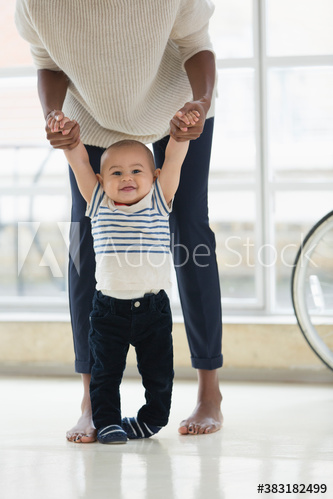 Portrait happy baby boy learning to walk with mother