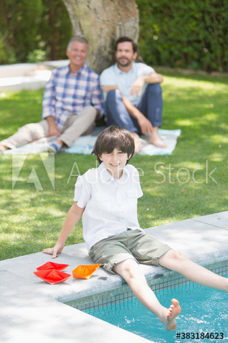 Portrait happy boy dipping feet in swimming pool