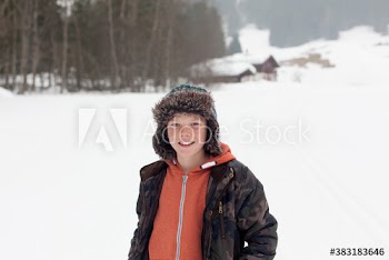 Portrait happy boy in fur hat in snowy field