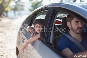 Portrait happy boy leaning out car window