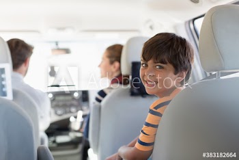 Portrait happy boy riding in backseat of car