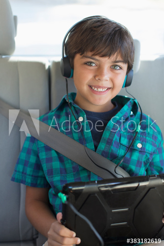 Portrait happy boy with headphones and digital tablet in car