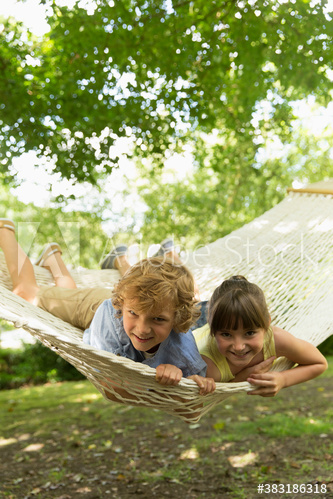 Portrait happy brother and sister relaxing in hammock