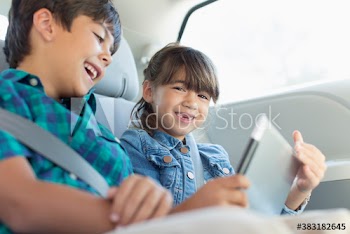 Portrait happy brother and sister with digital tablet in car