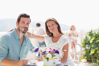 Portrait happy couple drinking coffee on sunny balcony