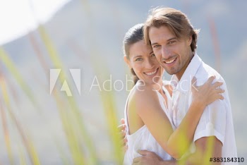 Portrait happy couple hugging in sunny grass