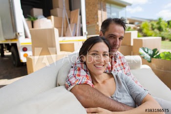Portrait happy couple on sofa outside moving van in driveway