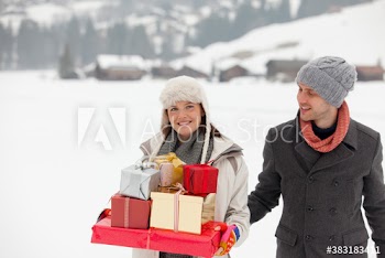 Portrait happy couple with Christmas gifts in snowy field