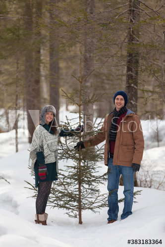 Portrait happy couple with Christmas tree in snowy woods