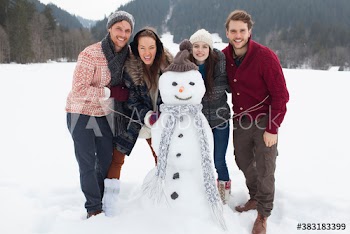 Portrait happy couples friends with snowman in snowy field