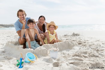 Portrait happy family making sandcastle on sunny beach