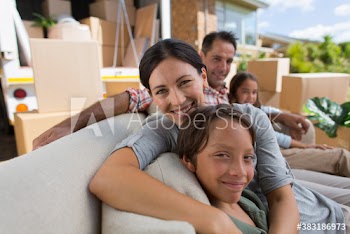Portrait happy family on sofa outside moving van in driveway