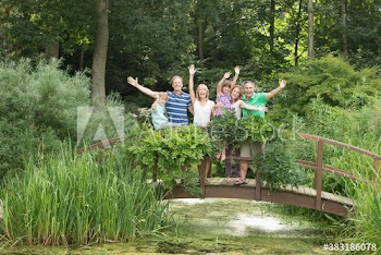 Portrait happy family waving on footbridge over pond