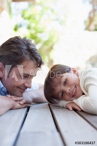 Portrait happy father and daughter laying on deck