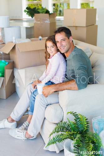 Portrait happy father and daughter on sofa with moving boxes