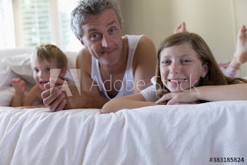 Portrait happy father and kids on bed