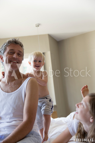 Portrait happy father and kids on bed