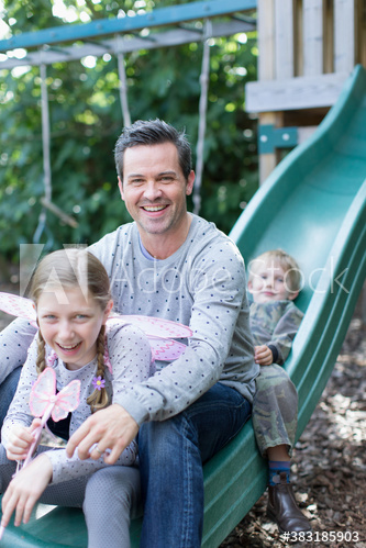 Portrait happy father and kids on playground slide