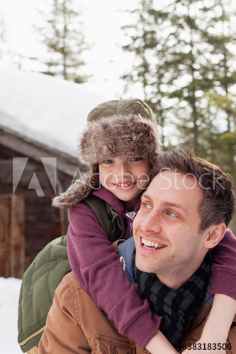 Portrait happy father and son piggybacking outside cabin