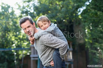 Portrait happy father piggybacking son at playground