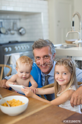 Portrait happy father with daughter and baby son in kitchen