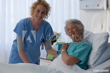 Portrait happy female nurse and senior patient in hospital room