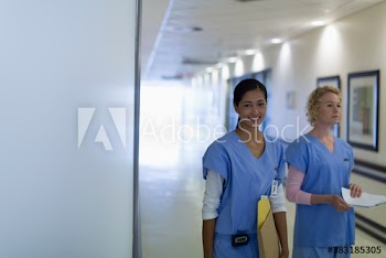 Portrait happy female nurses in hospital corridor