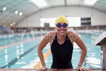 Portrait happy female swimmer at edge of swimming pool