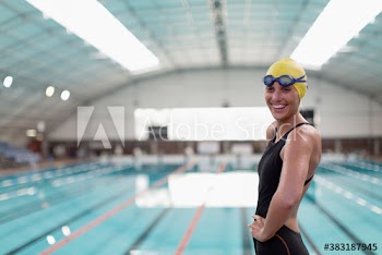 Portrait happy female swimmer at indoor swimming pool