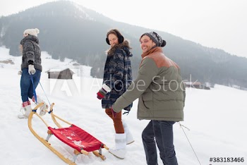 Portrait happy friends sledding in snowy field