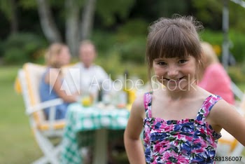 Portrait happy girl enjoying lunch with family in garden