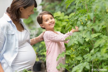 Portrait happy girl gardening with pregnant mother