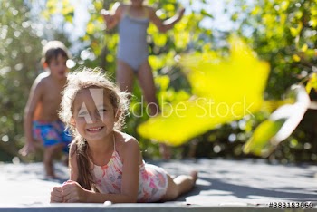 Portrait happy girl in bathing suit laying on sunny trampoline