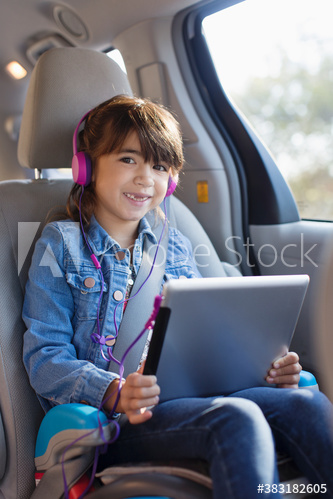 Portrait happy girl with digital tablet and headphones in car