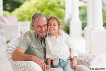 Portrait happy grandfather and granddaughter on patio