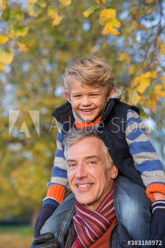 Portrait happy grandfather carrying grandson on shoulders in park